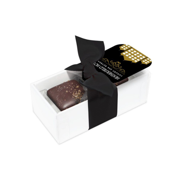 Two chocolate salted caramels in a transparent box wrapped in a black bow